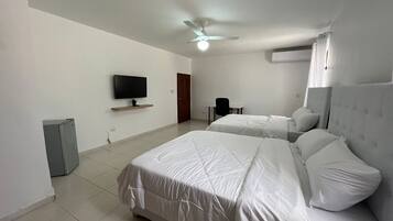 Habitación de hotel con dos camas, un televisor, ventilador de techo y aire acondicionado.