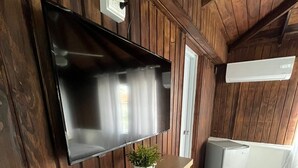 A modern kitchen with a built-in stainless steel refrigerator, a flat-screen TV mounted on a wooden wall, and a small potted plant on a wooden countertop. - El Montserrat - Hotel Boutique (Santiago de los Caballeros)