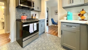 A modern kitchen with grey cabinets, a stainless steel stove, and a patterned backsplash.