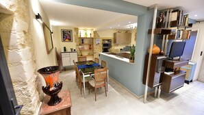 A modern kitchen with a dining area, featuring a glass-top table, wooden chairs, and a decorative vase. - Charming house in the heart of Provence (Cucuron)