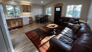 Amplia sala de estar con un sofá de cuero marrón y un comedor con sillas de madera y una mesa.