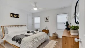 Ein Schlafzimmer mit Bett, Deckenventilator, Nachttisch, Blumentopf und Holzschrank.