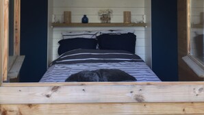 A wooden cabin interior with a bed, shelves, and a window. - A cozy and well-located chalet. (APPIETTO)