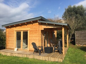 A wooden cabin with a covered patio, a sliding glass door, and outdoor seating.