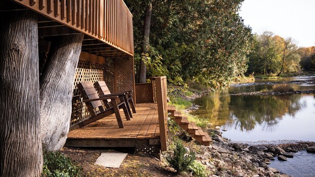 A wooden deck with lounge chairs, a wooden staircase, and a river view. - Charming Cottage on the River (South Bruce Peninsula)