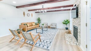A living room with a sofa, chairs, a coffee table, a fireplace, and a TV mounted on the wall.