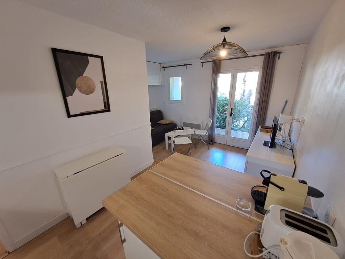 A compact kitchen with a wooden countertop, a white radiator, and a dining area with a table and chairs.