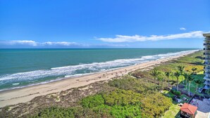 A beach view with a building on the right, including a balcony with a view of the ocean. - Lovely Fort Pierce Condo, Walk to Beach! (Fort Pierce)