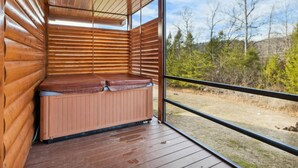Una baita in legno con sauna, ampie finestre e vista sulla foresta circostante.