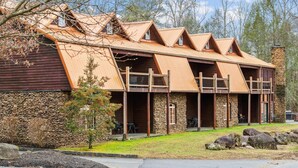 A row of log cabins with stone walls and wooden roofs, each with a balcony and a small window.