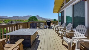 En uteplats med Adirondack-stolar, en grill och utsikt över bergen.