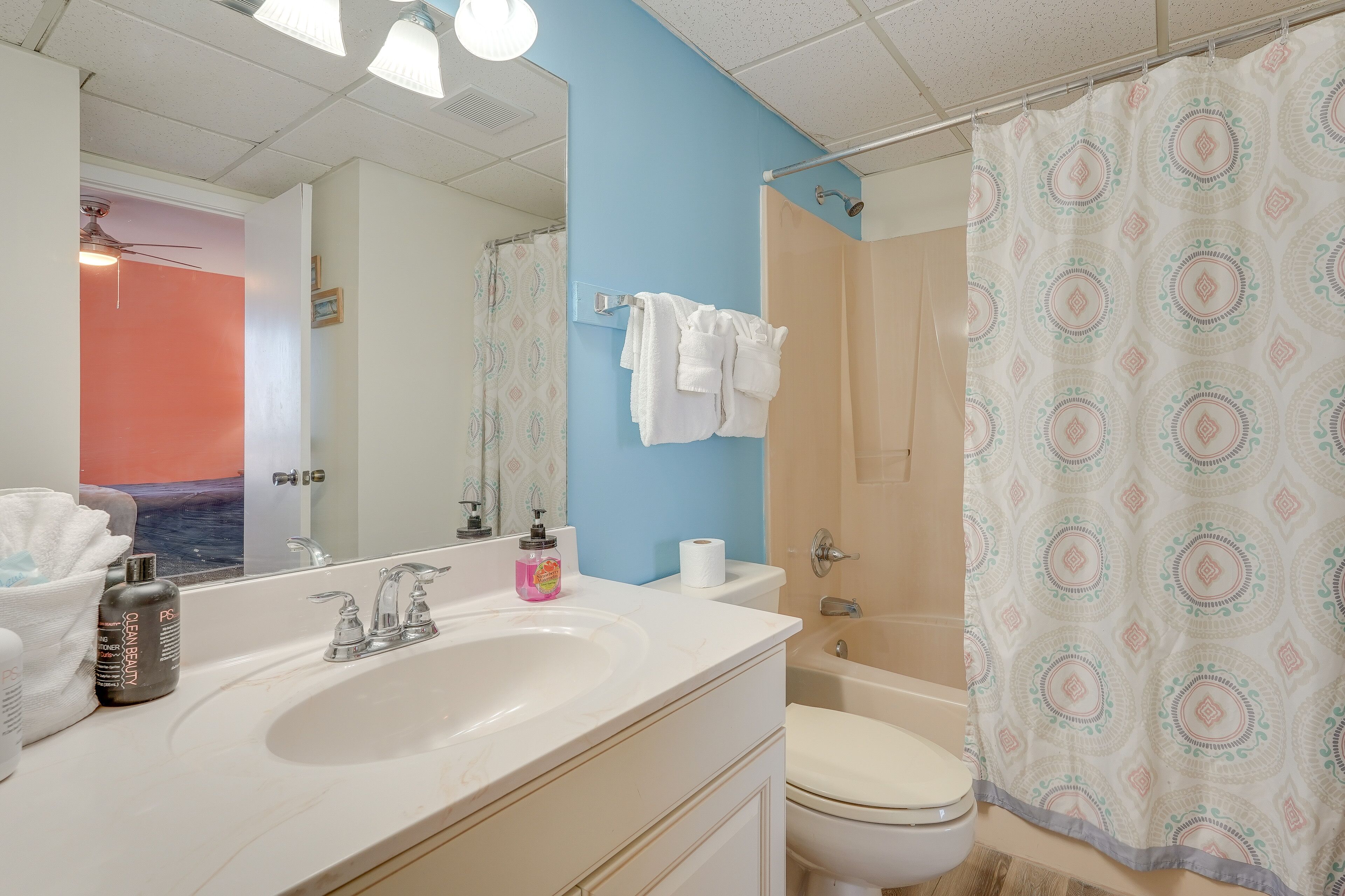A bathroom with a white sink, a mirror, a toilet, and a shower curtain.