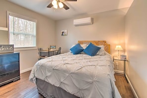Un dormitorio con cama, mesita de noche, cómoda, ventana con persianas, aire acondicionado y ventilador de techo.