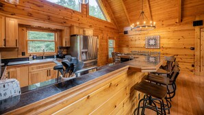 L’intérieur d’un chalet en bois comprend une cuisine, un coin repas et de grandes fenêtres.