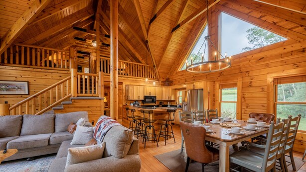 L’intérieur d’une cabane en bois comprend un espace de vie, une table à manger, une cuisine et un escalier.
