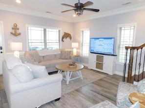 A living room with a sofa, armchair, coffee table, and a TV mounted on the wall.