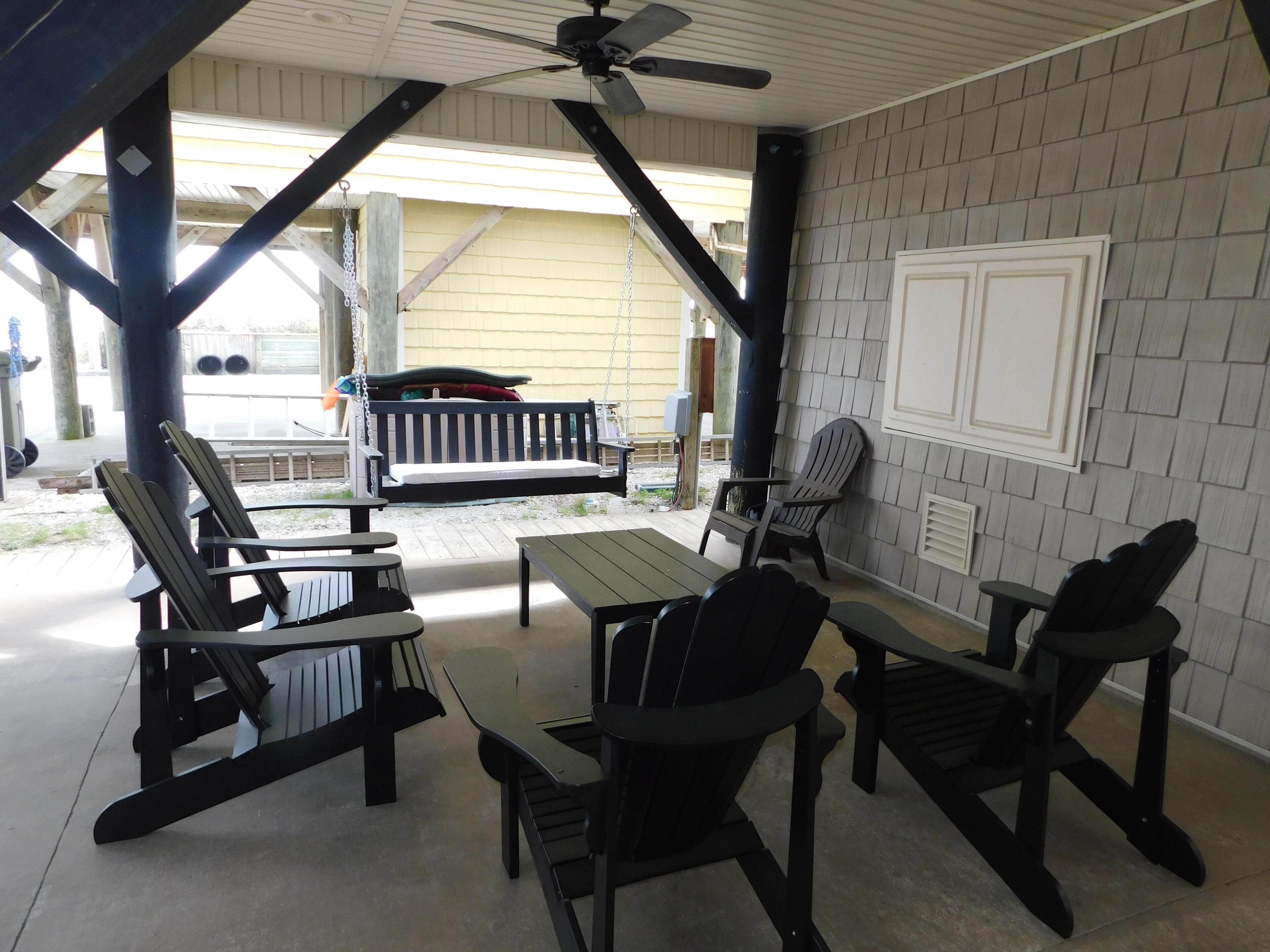 An outdoor patio with wooden furniture, a ceiling fan, and a brick wall.