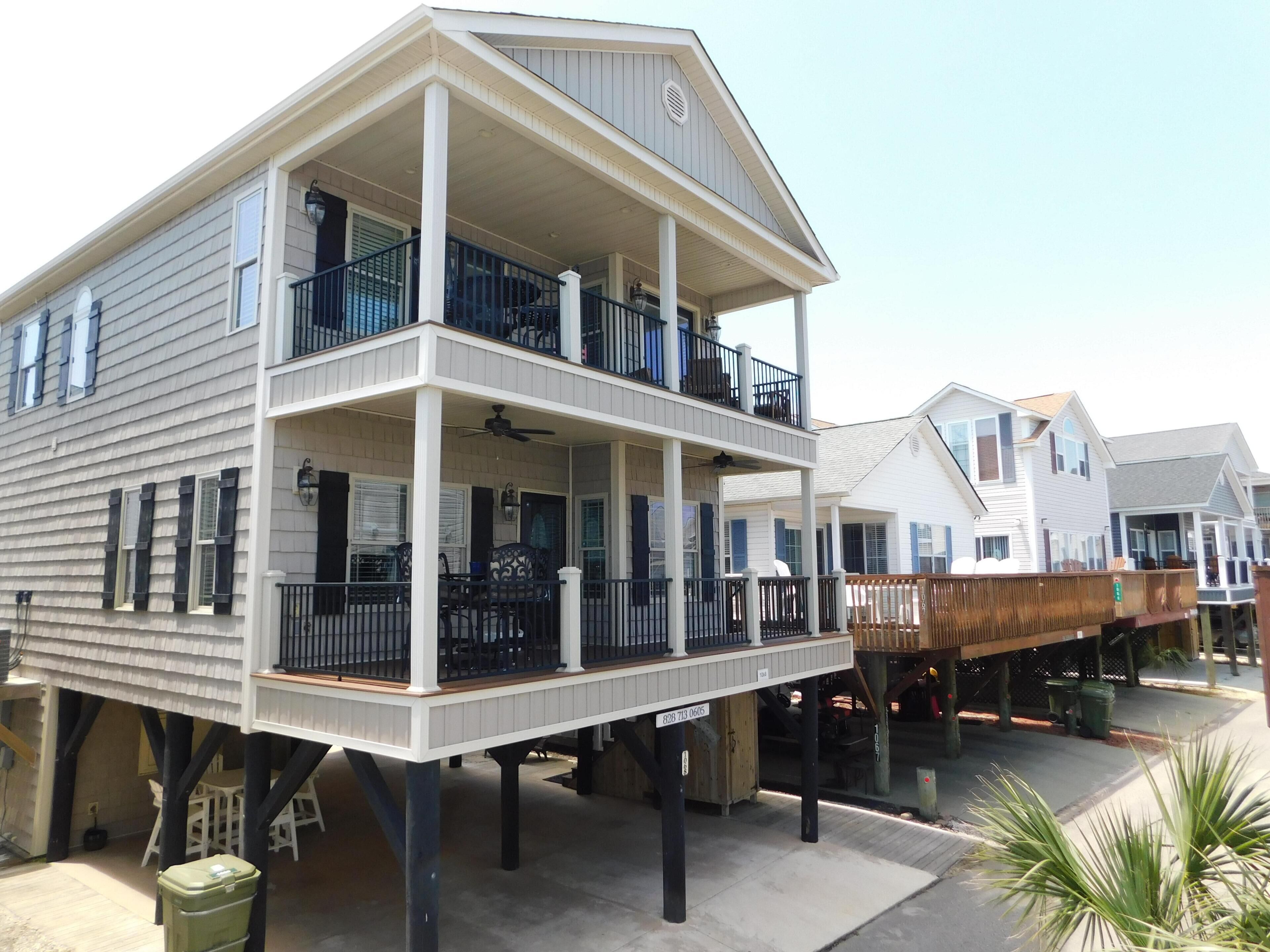 A two-story house with a balcony, a covered porch, and a wooden deck.