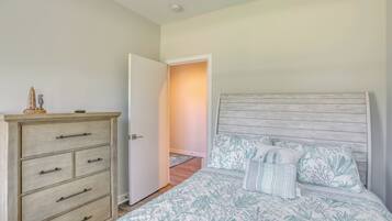 A bedroom with a bed, a wooden dresser, and an open door leading to another room.