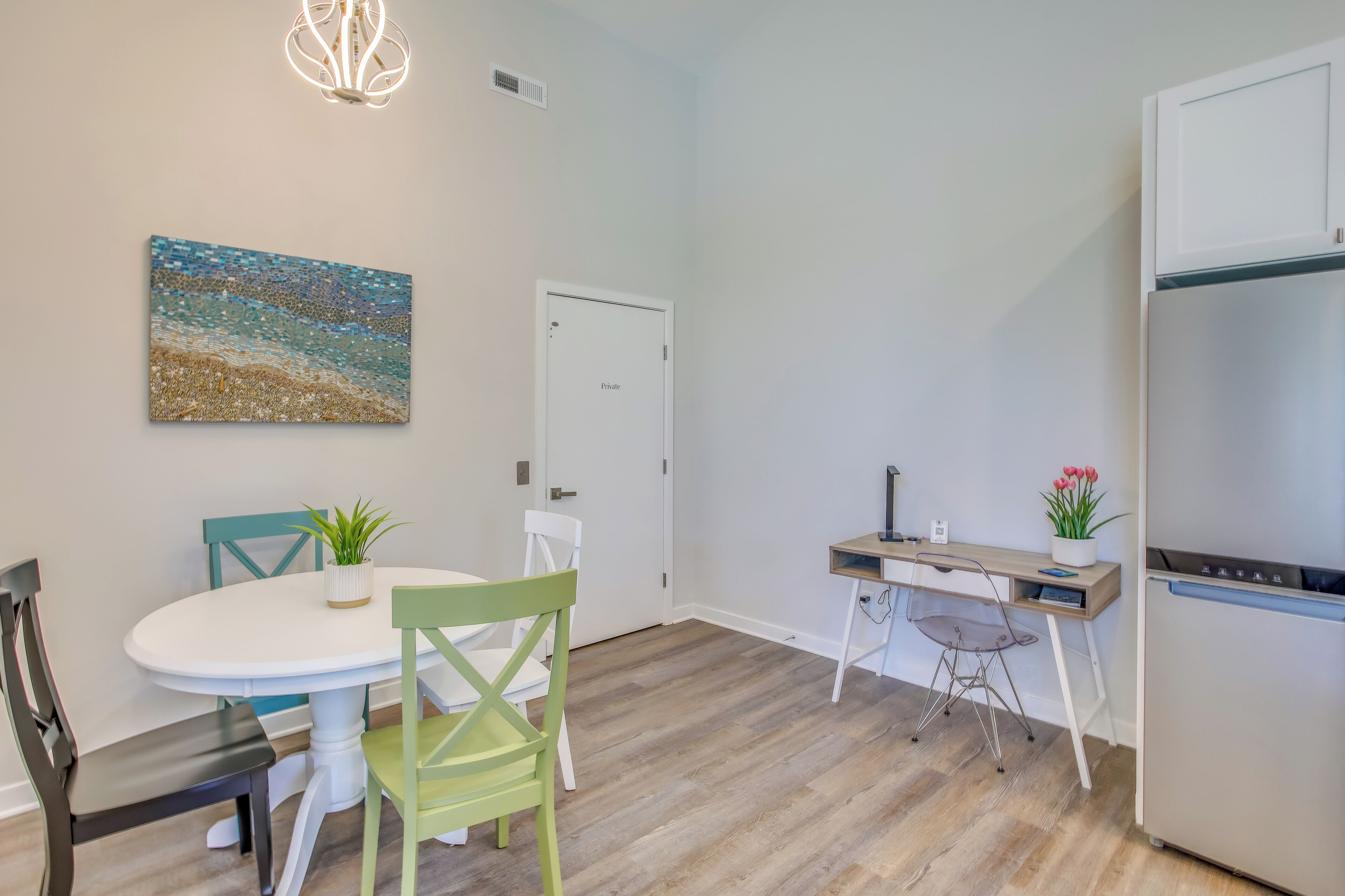 A modern kitchen with a white refrigerator, a wooden countertop, and a dining area with a white table and chairs.