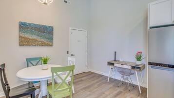 A modern kitchen with a white refrigerator, a wooden countertop, and a dining area with a white table and chairs.