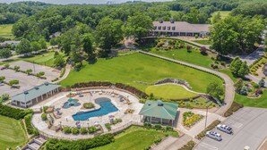 An aerial view of a resort with a swimming pool, a tennis court, and a large building.