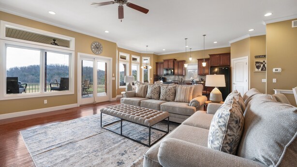 A spacious living room with a large sectional sofa, a coffee table, and a view of the outdoors through sliding glass doors.