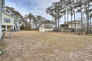 A residential area with a house, a covered porch, and a fenced yard. - Cozy Oak Island House < 1 Mi to Beaches! (Oak Island)