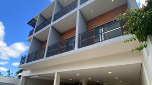 Un hotel de varios pisos con entrada cubierta, estacionamiento exterior y fachada de ladrillo.