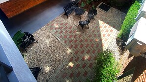 Un patio con pared de ladrillo, una escalera y mobiliario exterior.