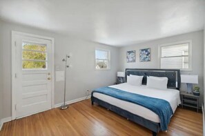 A bedroom with a bed, a nightstand, a floor lamp, and a door with a window.