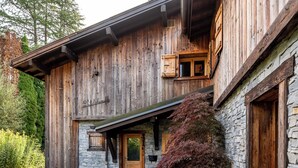 Ein rustikales Holzhaus mit Steinverkleidung, einer Holztür und einem großen Topfpflanzen im Eingangsbereich.