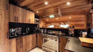 Eine moderne Küche mit Holzschränken, Edelstahlgeräten und einer schwarzen Arbeitsplatte.