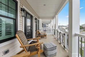 A covered porch with a seating area, including a chair and ottoman, and a view of the street.