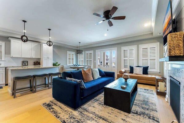A modern living room with a blue sofa, a coffee table, and a ceiling fan.