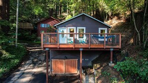 A cabin with a wooden deck, a covered entryway, and a small porch with chairs.
