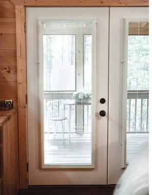 A wooden door with a glass panel, leading to an outdoor deck with a table and chairs. - Just Breathe! @ Fern Forest Cabin (Murphy)