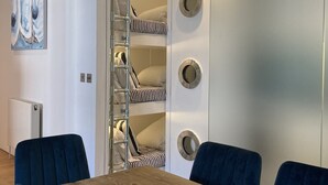 Una habitación con literas, una mesa de madera y sillas.