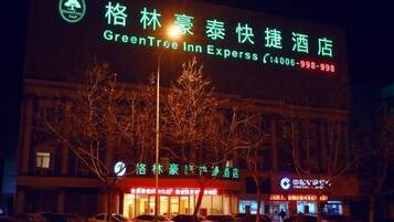 A hotel with a prominent GreenTree Inn Express sign, indicating it is part of the GreenTree Inn chain.