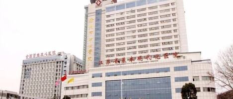 Un edificio de varios pisos con una entrada destacada y señalización que indica que es un hospital.
