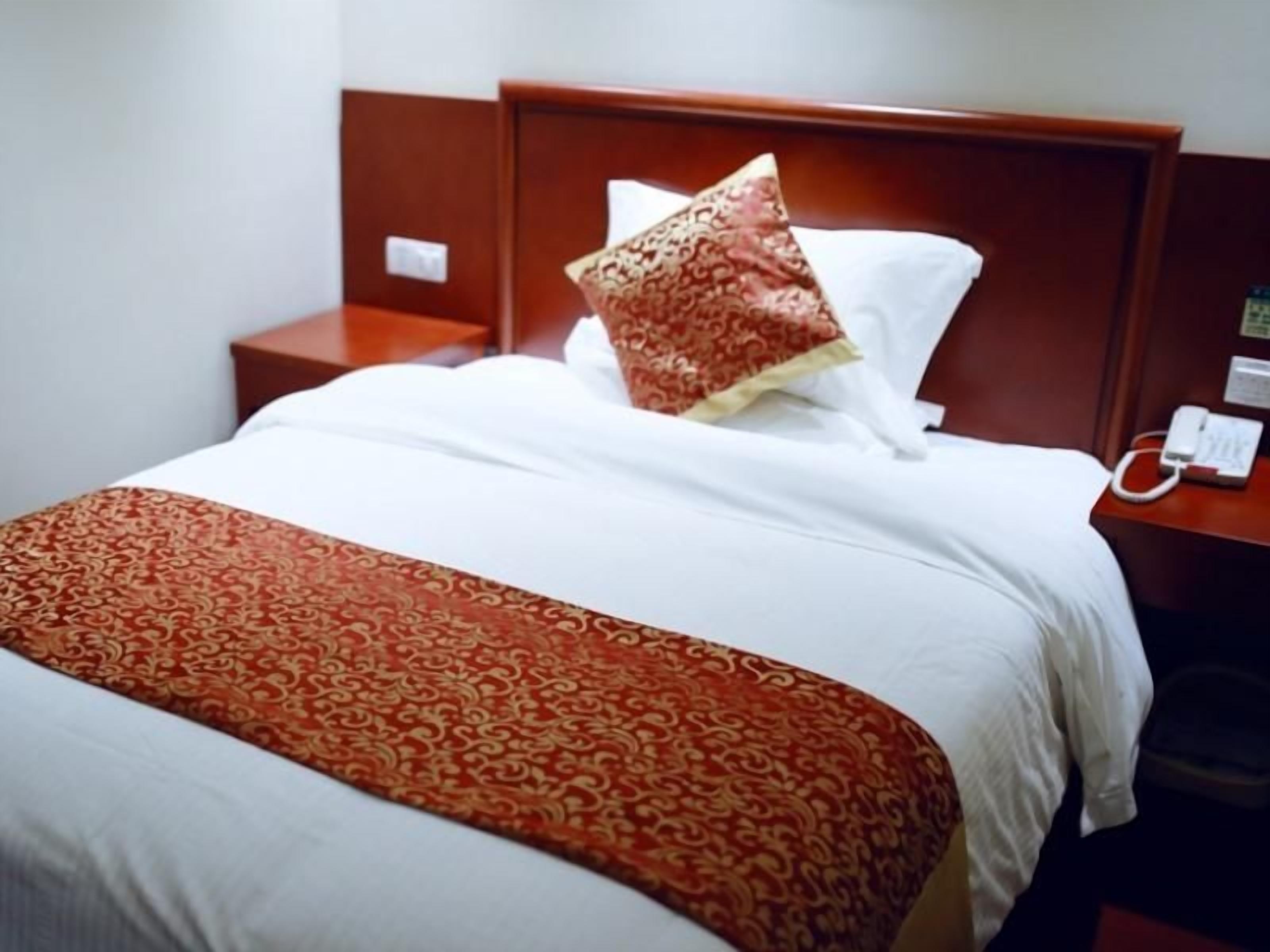 Une chambre d’hôtel avec un lit, une table de chevet avec un téléphone et une petite table de nuit.