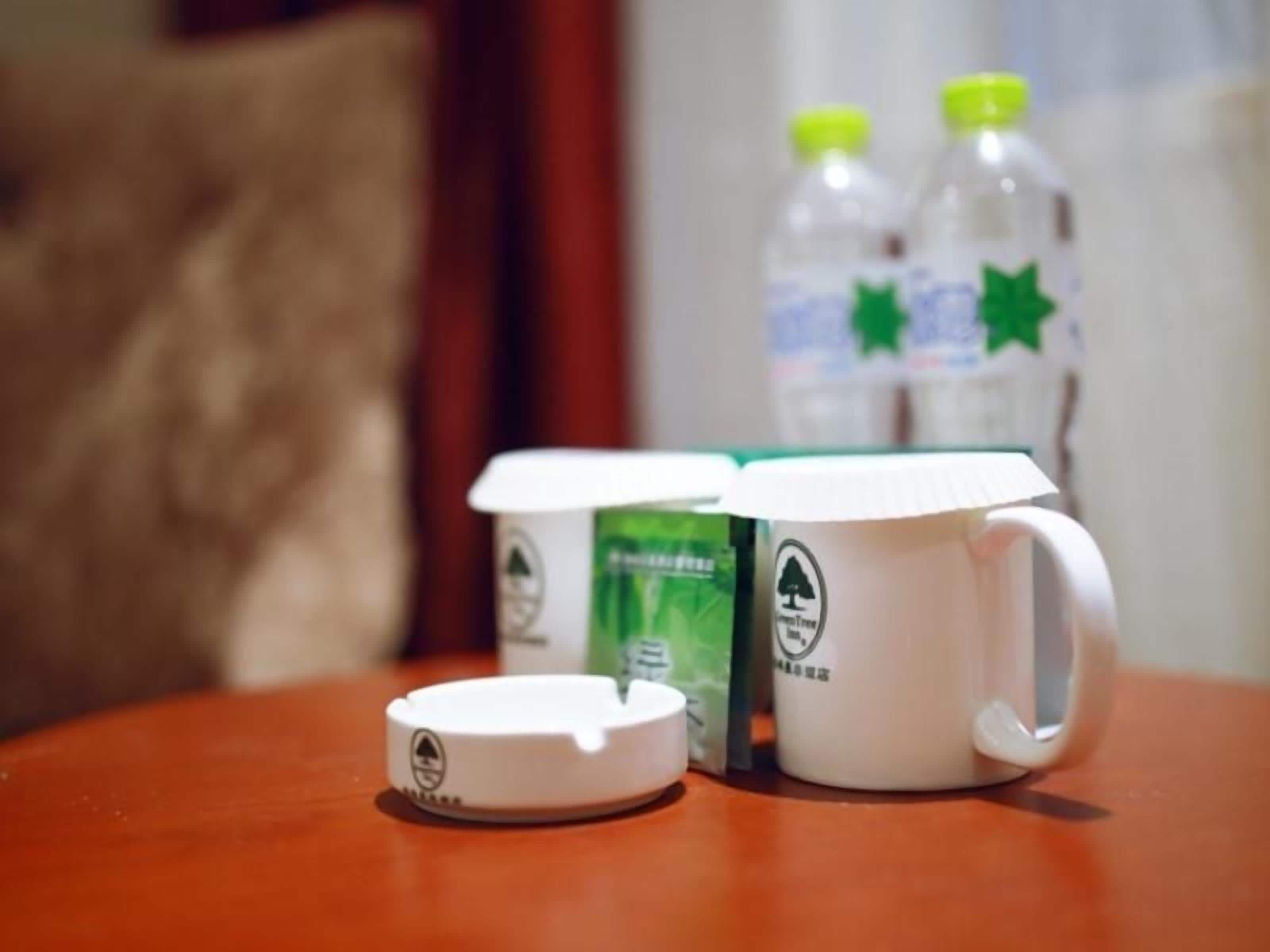 A white mug with a handle and a lid on a wooden table.