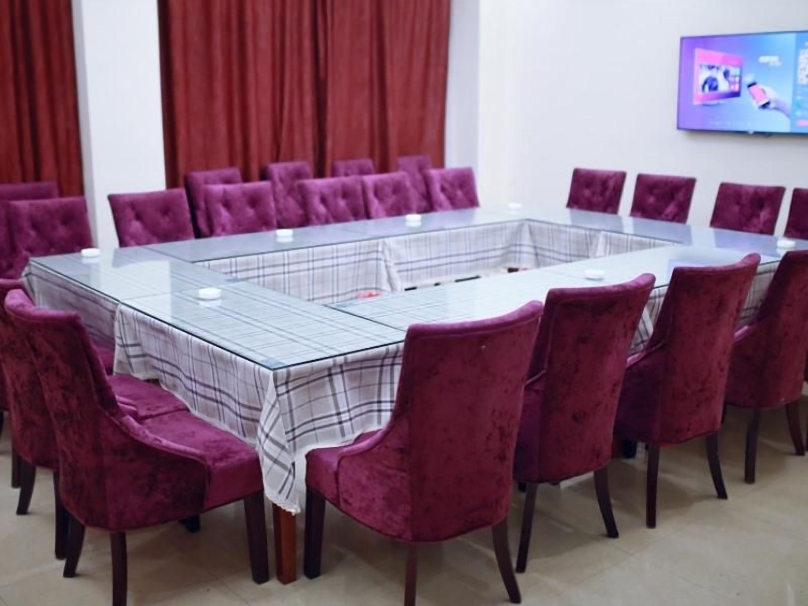 A conference room with a glass table and purple velvet chairs.