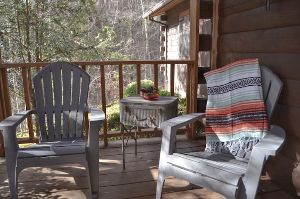 Une terrasse en bois avec deux fauteuils Adirondack et une petite table sur laquelle se trouve un panier.