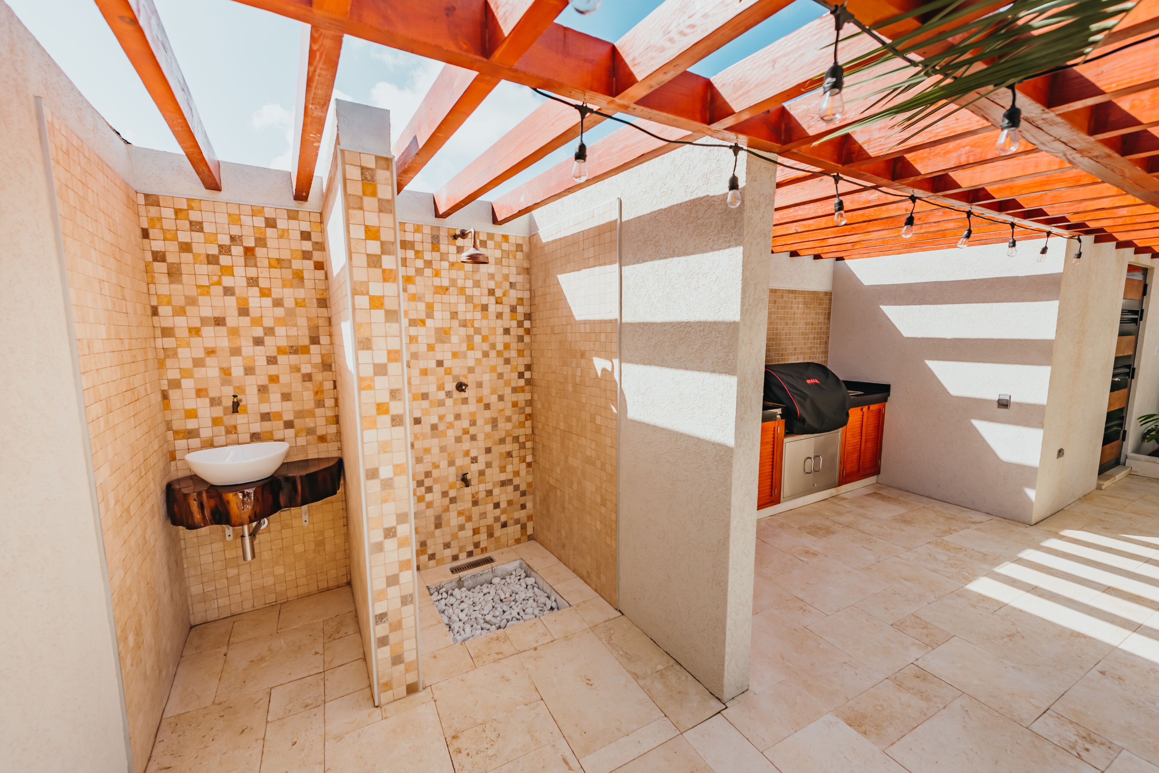 Ein Badezimmer mit einer Wand aus Mosaikfliesen, einem Waschbecken und einer Duschkabine.