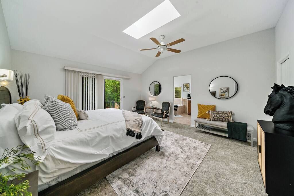 Ein Schlafzimmer mit einem Bett, einem Deckenventilator, einem Oberlicht, einer Couch, einem Sessel, einem Spiegel und einer Pferdestatue.