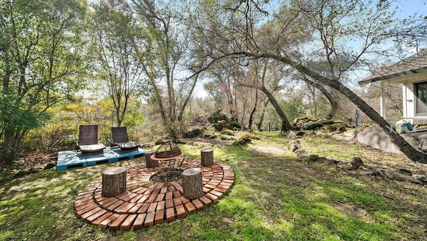 Un espacio de estar al aire libre circular con un brasero, rodeado por un anillo de ladrillo y dos sillones de descanso.