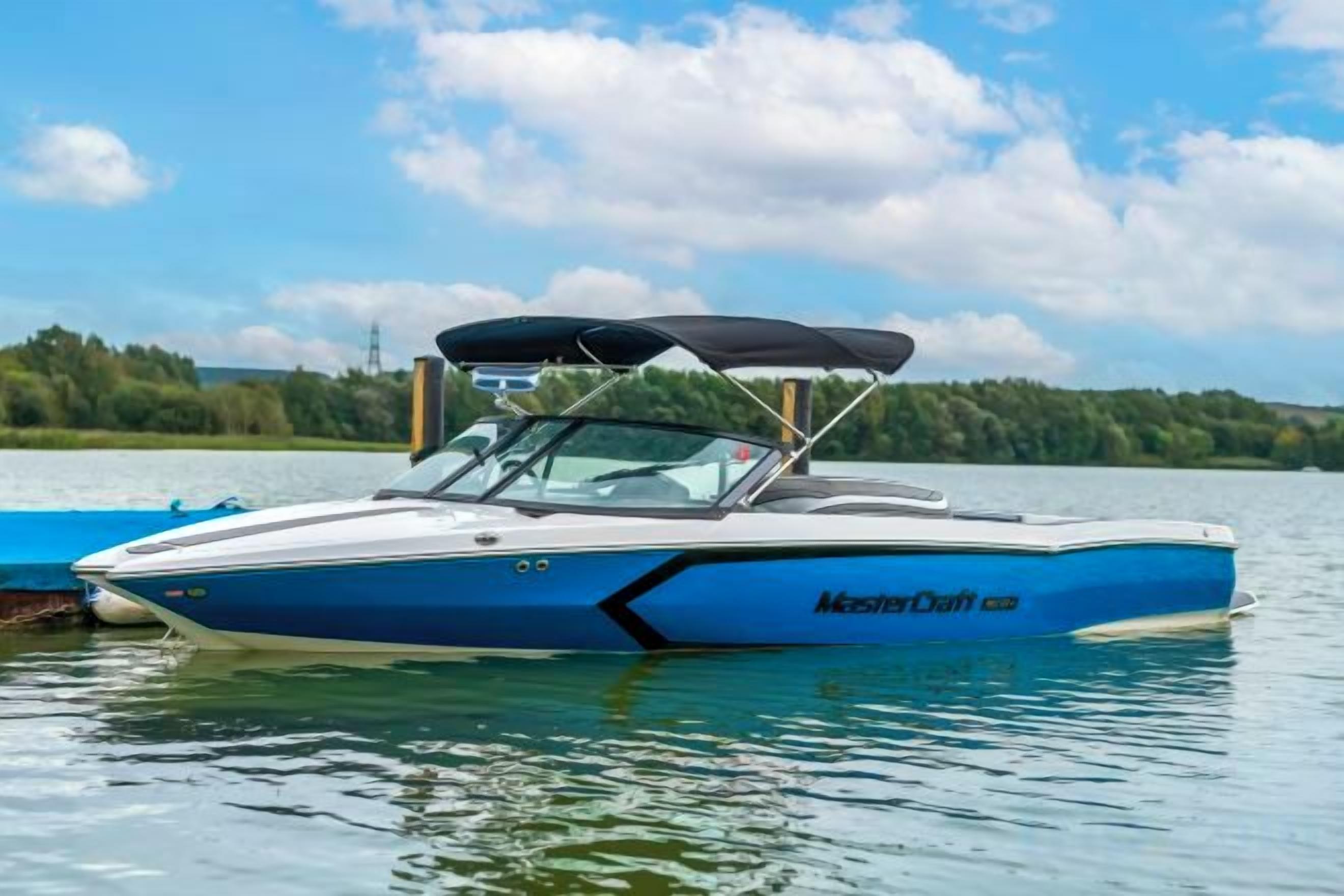 A blue and white speedboat with a canopy, docked on calm water.