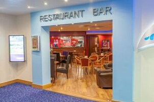 Un bar restaurante con zona de bar, asientos y una barra.