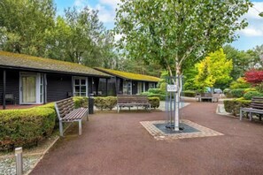 A covered outdoor area with benches and a pathway leading to a building with a sloped roof. - Pine Lake Resort (LANCASHIRE)